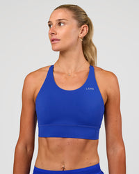 Woman wearing Accelerate Split Strap Sports Bra - Electric Indigo | Model:Emelia | Size:XS | Thumbnail Index: 2