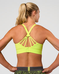 Woman wearing Accelerate Split Strap Sports Bra - Hyper Green | Model:Emelia | Size:XS | Thumbnail Index: 0