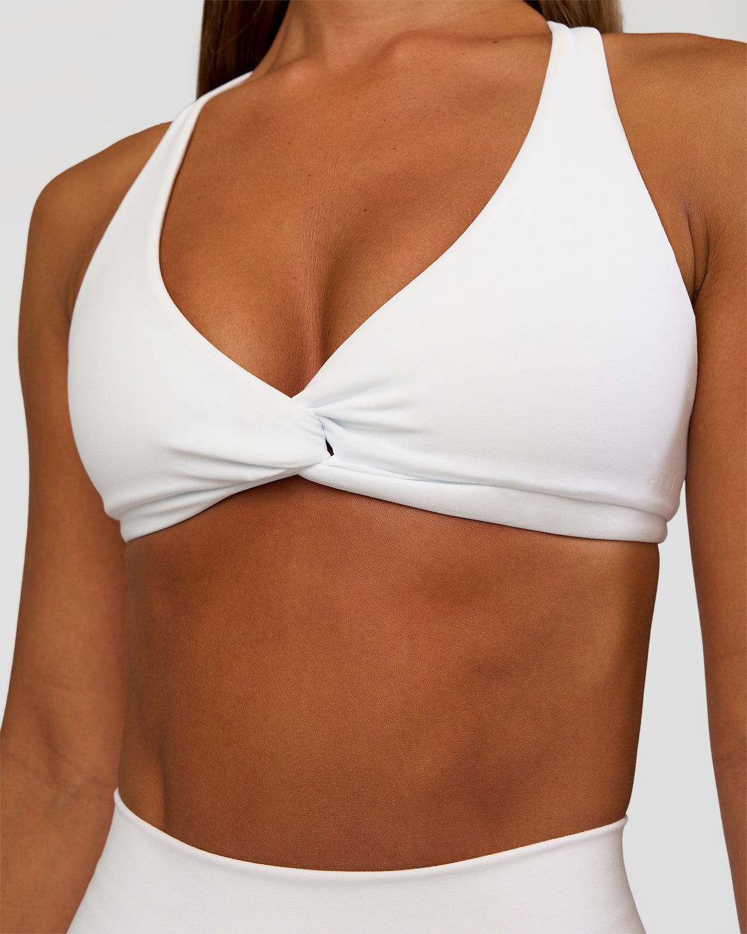 Woman wearing Aspire Twist Sports Bra - White | Model:Brylee | Size:XS - view 4
