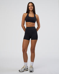 Woman wearing Elite High-Rise 4" Short Pockets - Black | Model:Eliza | Size:XS | Thumbnail Index: 1