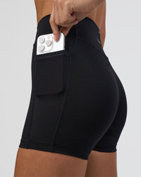 Woman wearing Elite High-Rise 4" Short Pockets - Black | Model:Eliza | Size:XS | Thumbnail Index: 2