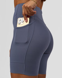 Woman wearing Elite Run High-Rise 7" Short Pockets - Night Shadow | Model:Brylee | Size:XS | Thumbnail Index: 1