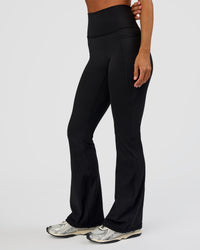 Woman wearing Fusion Ultra High-Rise Flared Petite Legging Pockets - Black | Model:Brylee | Size:XS | Thumbnail Index: 1