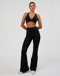 Woman wearing Fusion V-Contour High-Rise Flared Legging Pockets - Black | Model:Charli | Size:XS | Thumbnail Index: 2