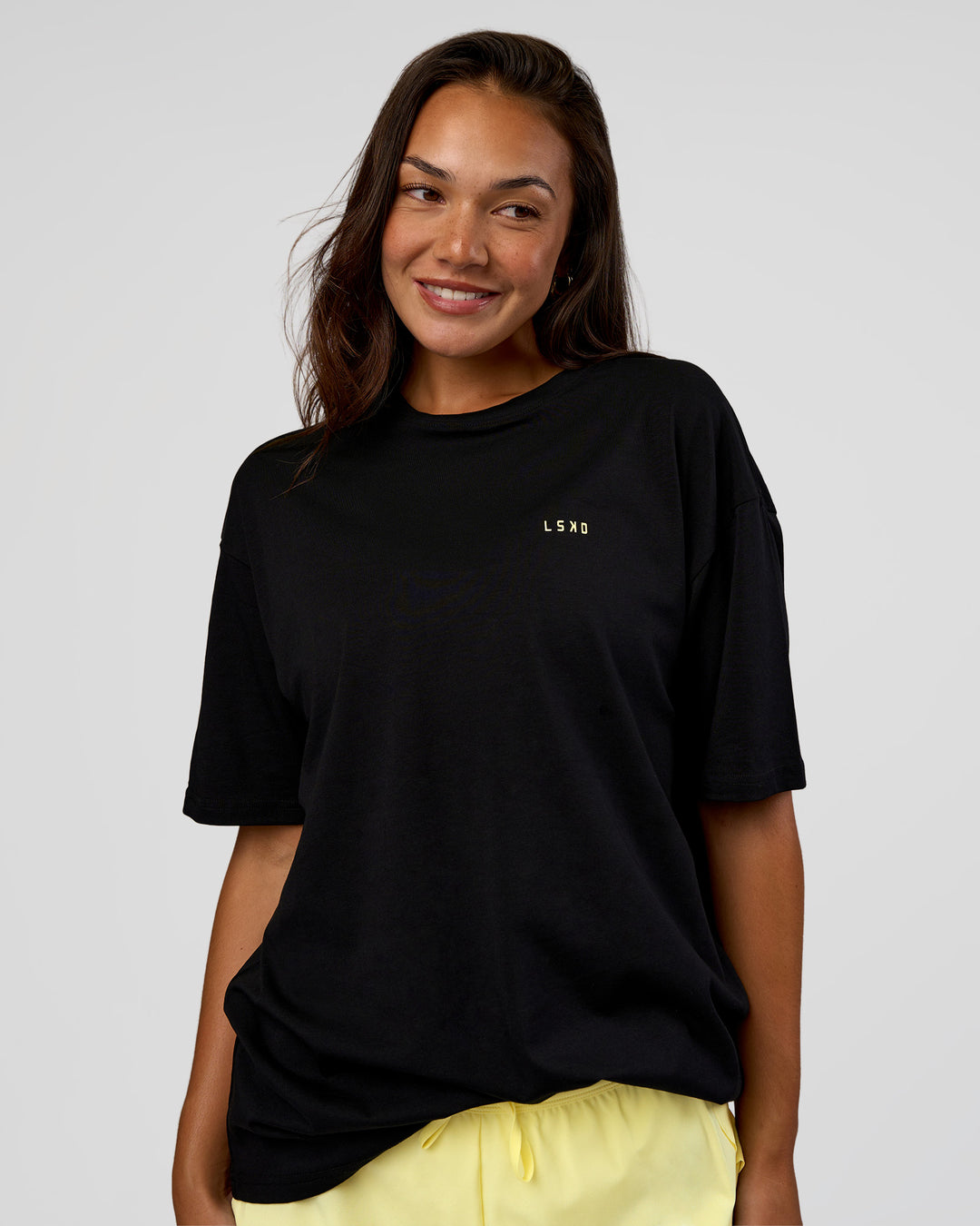 Woman wearing High Run FLXCotton Oversized Tee - Black-Yellow Fizz | Model:Kirstyn | Size:XS - view 4