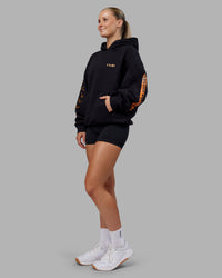 Woman wearing Hyped Unisex Oversized Hoodie - Black-Vibrant Orange | Model:Neve | Size:XS | Thumbnail Index: 5