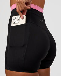 Woman wearing Liberate High-Rise 4" Short Pockets - Black-Candy Pink | Model:Brylee | Size:XS | Thumbnail Index: 1