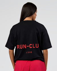 Woman wearing RUN CLUB FLXCotton Tee Oversize - Black-Scarlet | Model:Rhiley | Size:XS | Thumbnail Index: 1