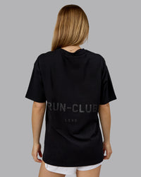 Woman wearing RUN CLUB FLXCotton Tee Oversize - Black-Reflective | Model:Emilie | Size:XS | Thumbnail Index: 1
