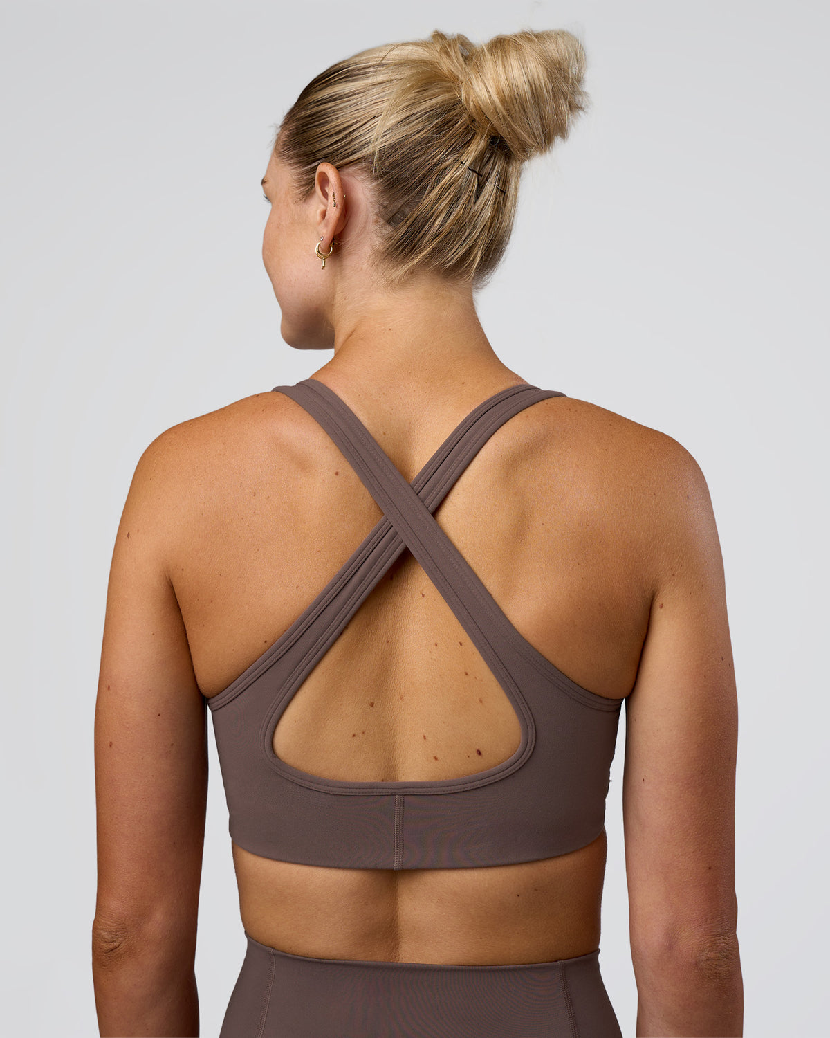 Woman wearing Stamina Sports Bra - Peppercorn | Set:true | Angle:back | Model:Emelia | Size:XS