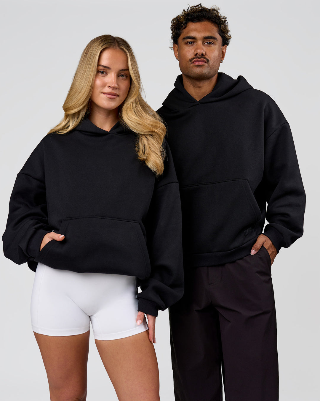 Duo wearing Tonal Legacy Boxy Hoodie - Black-Black | Model:Issy | Size:XS | Model:Xav | Size:L - view 1