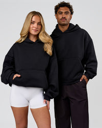 Duo wearing Tonal Legacy Boxy Hoodie - Black-Black | Model:Issy | Size:XS | Model:Xav | Size:L | Thumbnail Index: 0