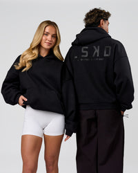 Duo wearing Tonal Legacy Boxy Hoodie - Black-Black | Model:Issy | Size:XS | Model:Xav | Size:L | Thumbnail Index: 3