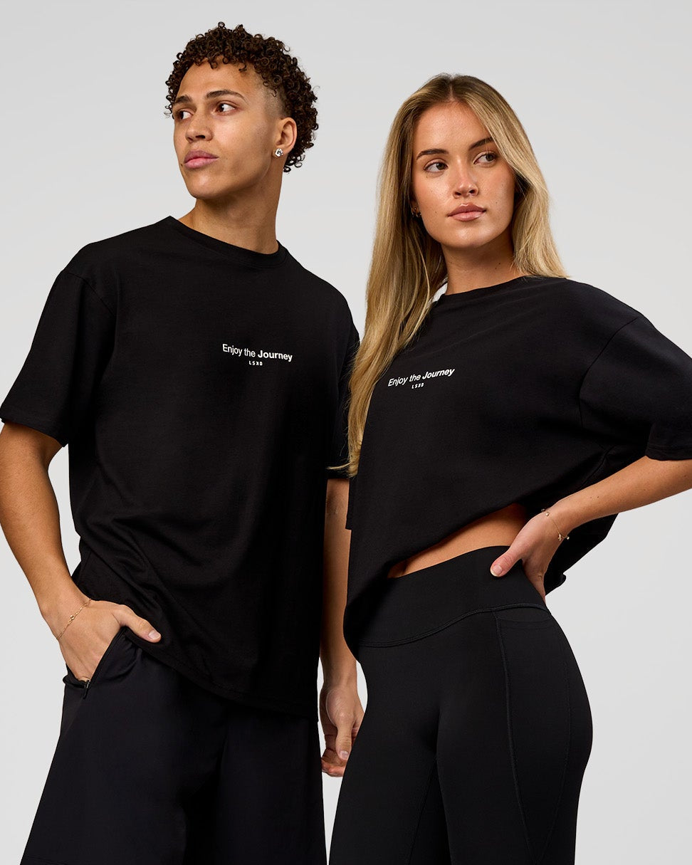 Duo wearing VS1 Enjoy The Journey FLXCotton Oversize Tee - Black | Model:Issy | Size:XS | Model:Leandro | Size:M - view 1