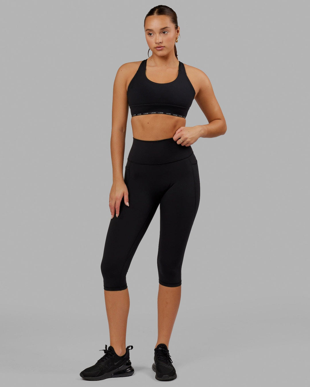 Woman wearing O.G. Fusion Ultra High-Rise 3/4 Legging Pockets - Black | Model:Milly | Size:S - view 2