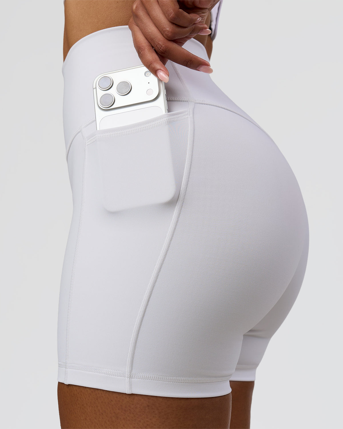 Woman wearing Fusion V-Contour Ultra High-Rise 4" Short Pockets - White | Model:Jordan | Size:S - view 2