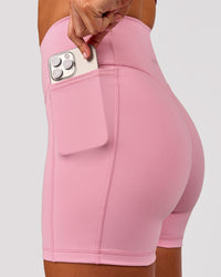 Woman wearing Fusion V-Contour Ultra High-Rise 4" Short Pockets - Pink Rose | Model:Charli | Size:XS | Thumbnail Index: 0