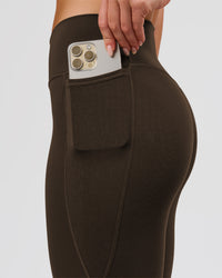 Woman wearing Fusion V-Contour High-Rise Flared Petite Legging Pockets - Ground Coffee | Model:Issy | Size:XS | Thumbnail Index: 4