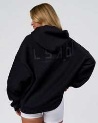 Woman wearing Tonal Legacy Boxy Hoodie - Black-Black | Model:Issy | Size:XS | Thumbnail Index: 2