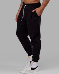 Man wearing Unisex Capsule Track Pant - Black | Thumbnail Index: 1